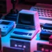 Retro computers and gaming consoles under neon lighting